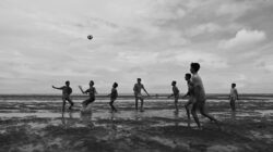 Sekelompok anak laki-laki yang bermain sepak bola dengan antusias di pantai di Chattogram, Bangladesh.