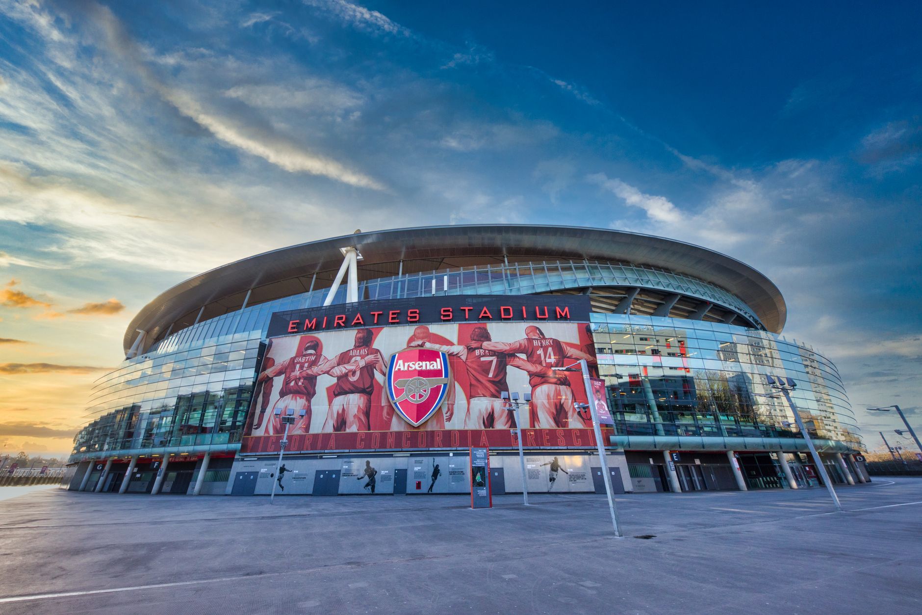 Pemandangan Emirates Stadium, rumah Arsenal FC di London, menampilkan arsitektur modern di bawah langit yang cerah.