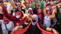 Kerumunan yang meriah merayakan dengan antusiasme dan syal warna-warni di Jawa Barat, Indonesia.