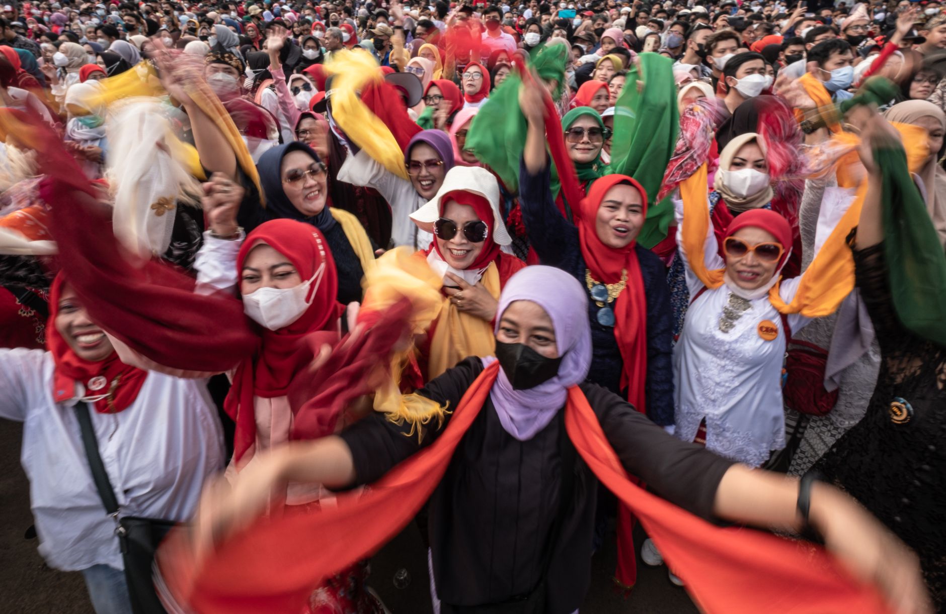 Kerumunan yang meriah merayakan dengan antusiasme dan syal warna-warni di Jawa Barat, Indonesia.