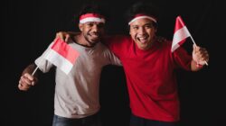 Dua pemuda merayakan persatuan Indonesia dengan bendera dan senyuman di Yogyakarta.