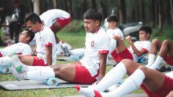 Pemain sepak bola dalam sesi latihan melakukan peregangan di lapangan di Jakarta.