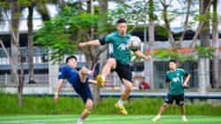 Atlet dalam pertandingan sepak bola yang mendebarkan, menunjukkan keterampilan dan kerja tim di lapangan di Hanoi.