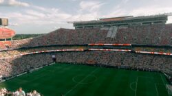 Pandangan udara pertandingan sepak bola yang ramai di stadion luar ruangan yang dipenuhi dengan penggemar yang antusias.