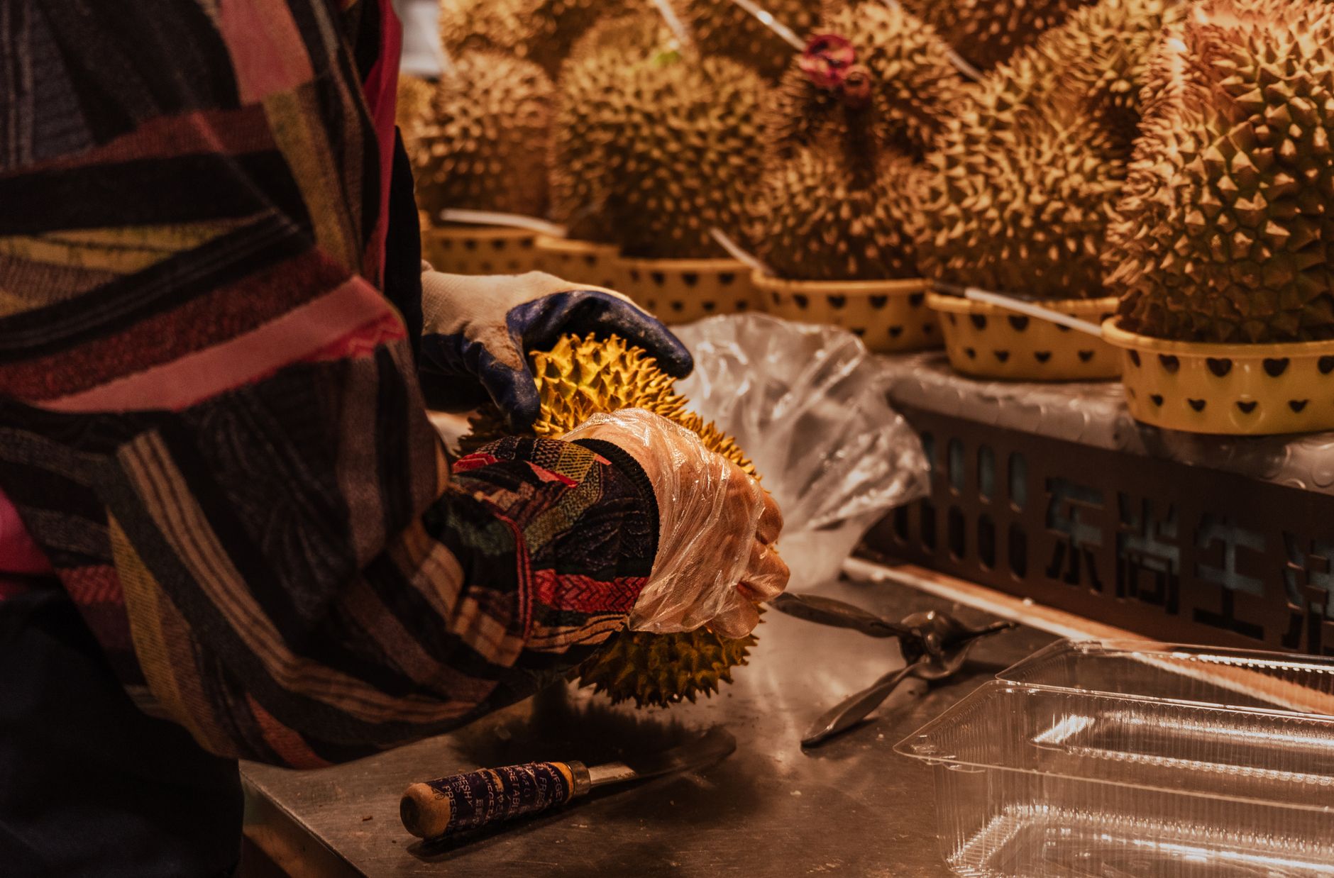 Seseorang yang menangani buah durian dengan hati-hati di lingkungan pasar.