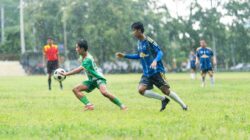 Para pemain dalam pertandingan sepak bola di tengah hujan menunjukkan tekad dan kerja sama tim.