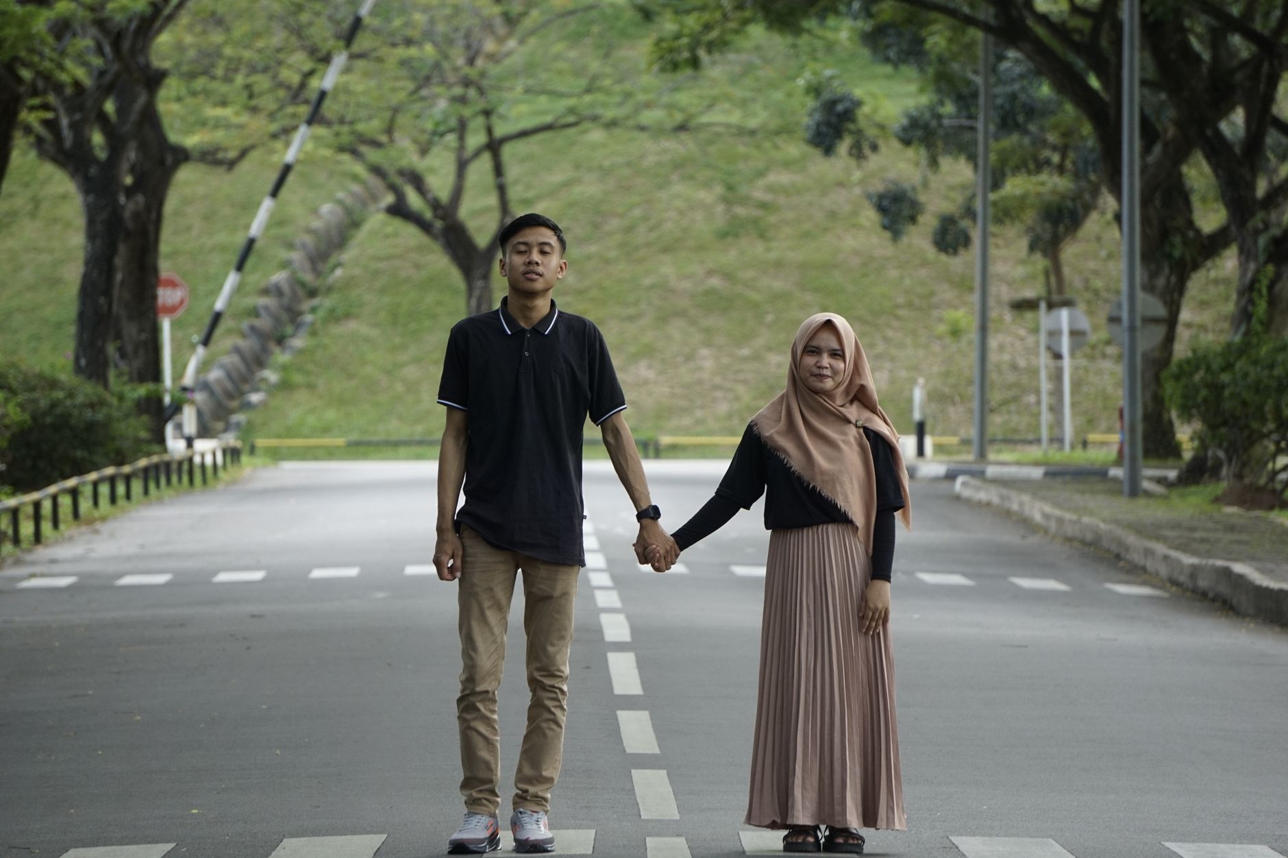 Sekumpulan pasangan muda berdiri di jalan yang tenang, bergandeng tangan dan menikmati momen damai di luar ruangan.