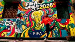 Mural berwarna-warni Piala Dunia FIFA 2026 dengan anak-anak bermain sepak bola di latar depan.