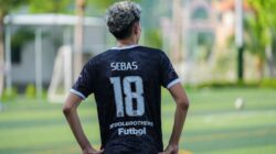 Tampilan belakang pemain sepak bola yang mengenakan jersey nomor 18 di hari yang cerah di luar ruangan.