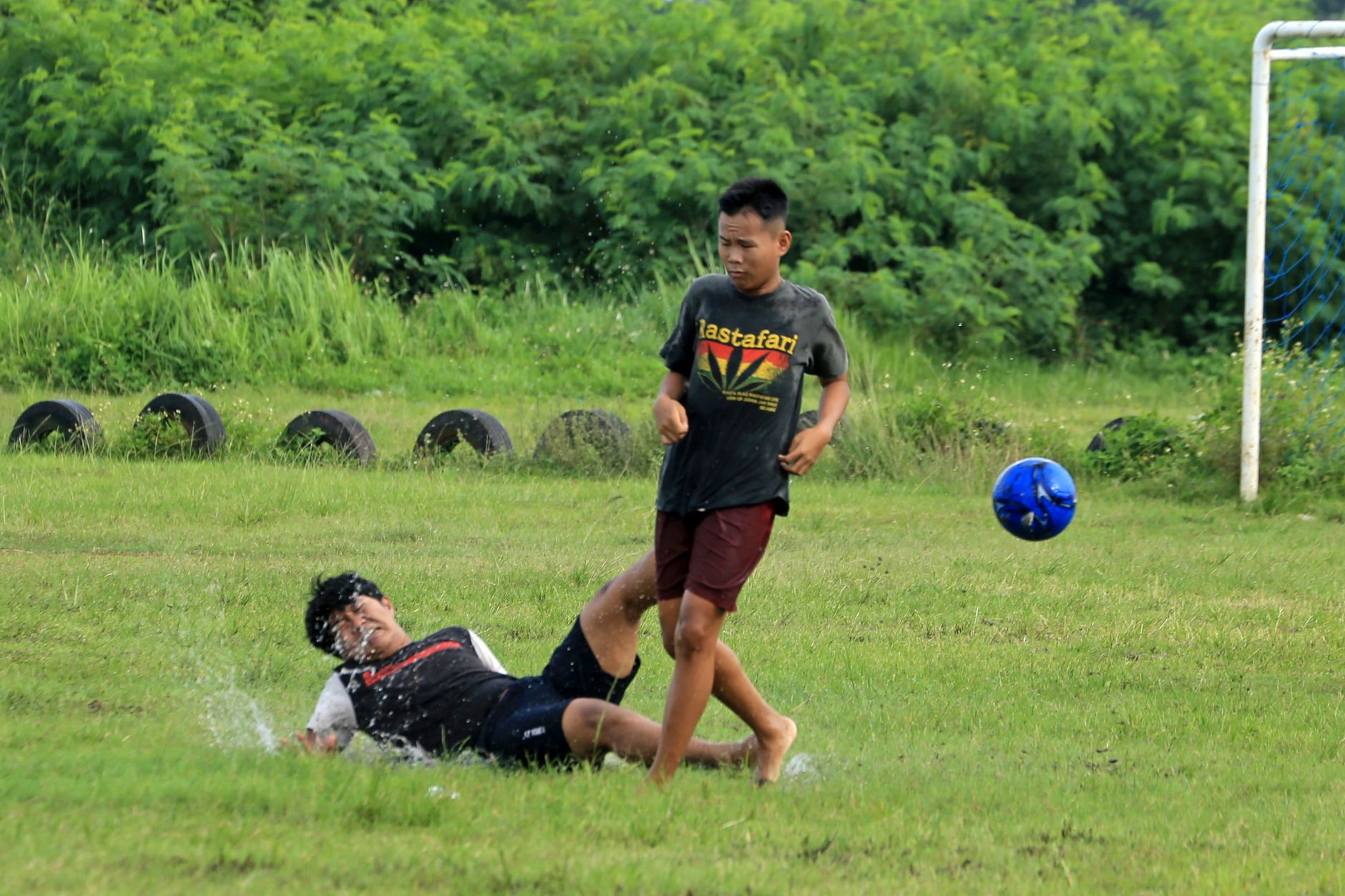 Dua remaja terlibat dalam pertandingan sepak bola yang seru di lapangan berumput, menampilkan aksi dan sportivitas.