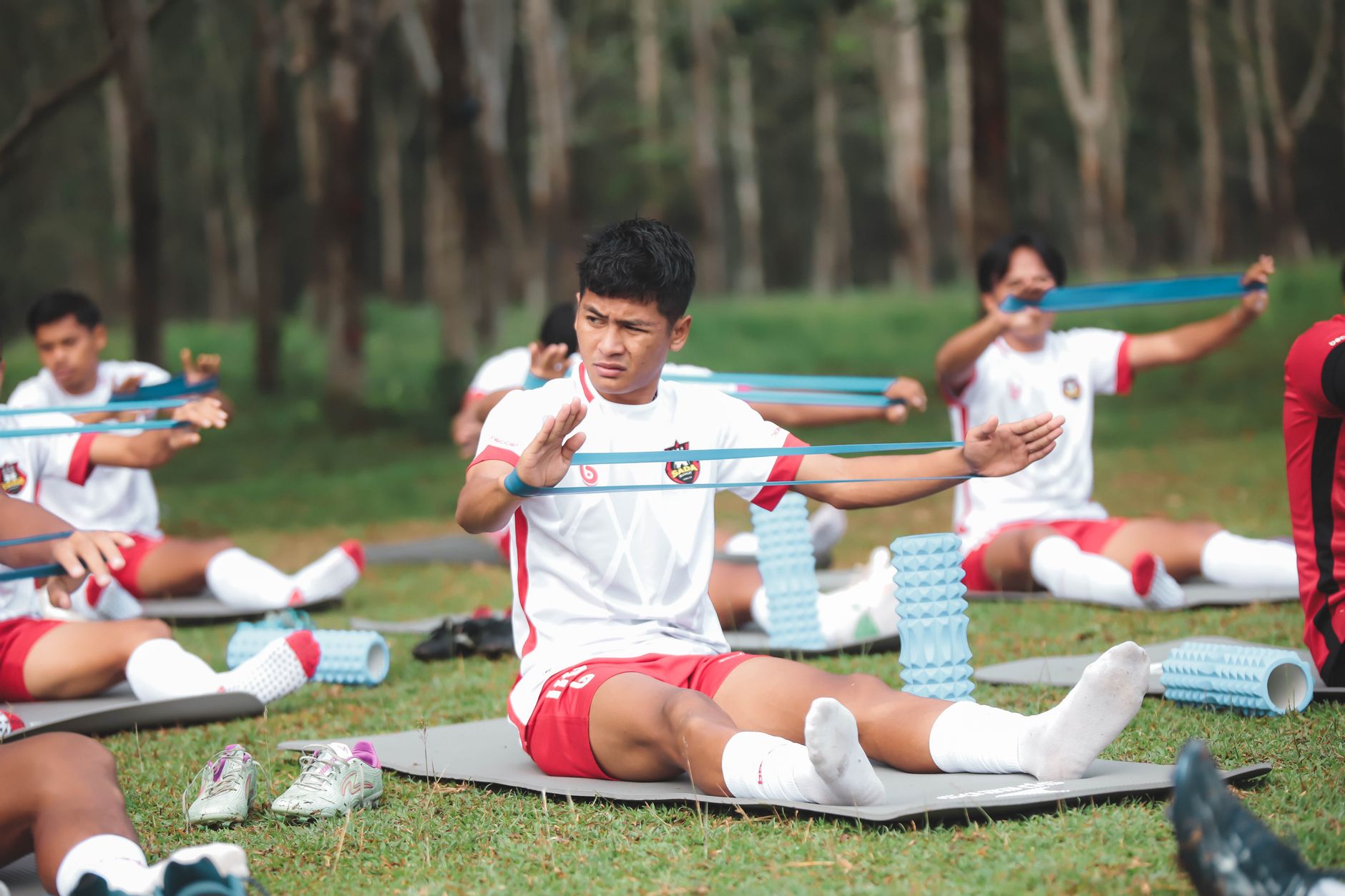 Sekelompok pemain sepak bola muda berlatih dengan band resistensi di luar ruangan di Jakarta, Indonesia.
