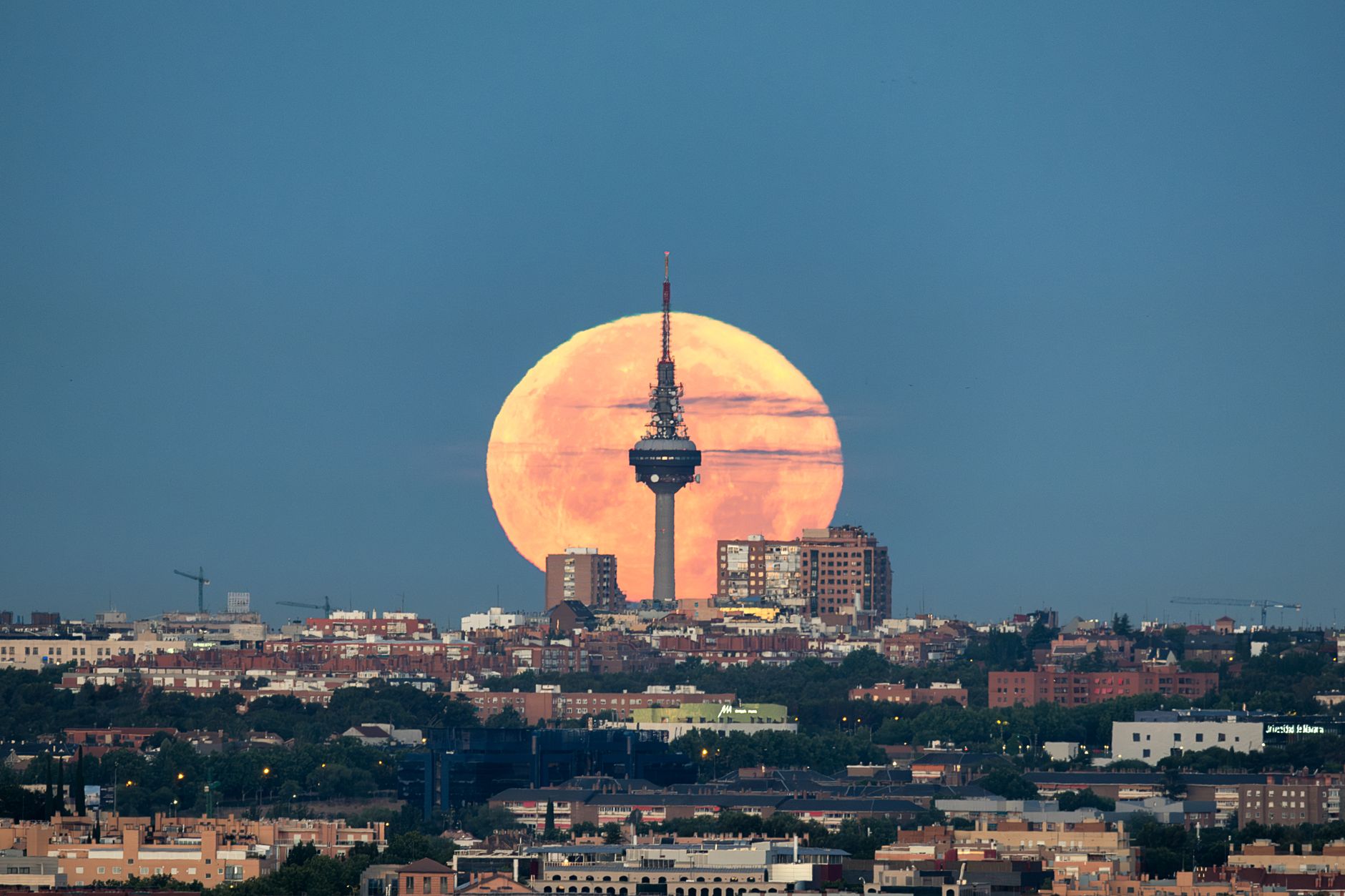 Bulan purnama yang menawan terbit di balik cakrawala Madrid dengan menara komunikasi yang ikonik.