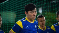 Tim sepak bola Asia berkumpul dalam seragam yang cerah selama pertandingan malam. Fokus pada kerja tim dan sportivitas.