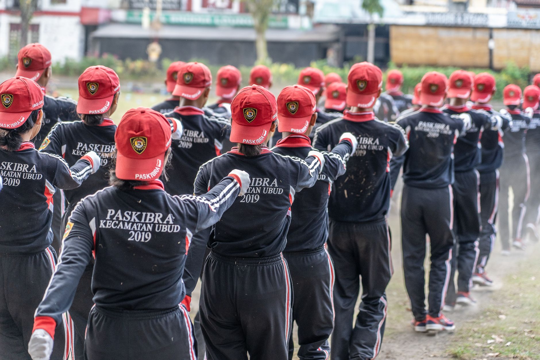 Sekelompok orang dalam seragam yang serasi dan topi merah berdiri dalam formasi di luar ruangan.