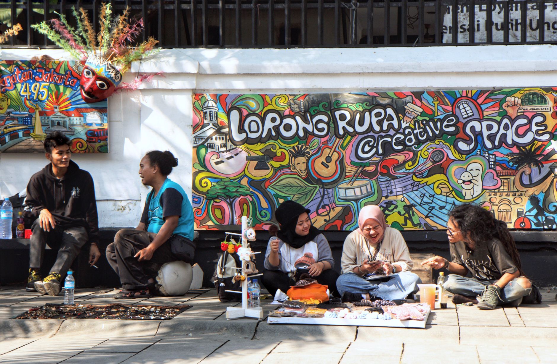 Pemandangan jalanan penuh warna dengan mural semarak dan beragam kelompok teman di Jakarta.