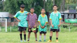 Empat anak laki-laki muda berseragam sepak bola berpose di lapangan rumput di Myawaddy, Myanmar.