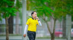 Seorang wasit berbaju kuning meniup peluit selama pertandingan sepak bola di Hanoi, Vietnam.