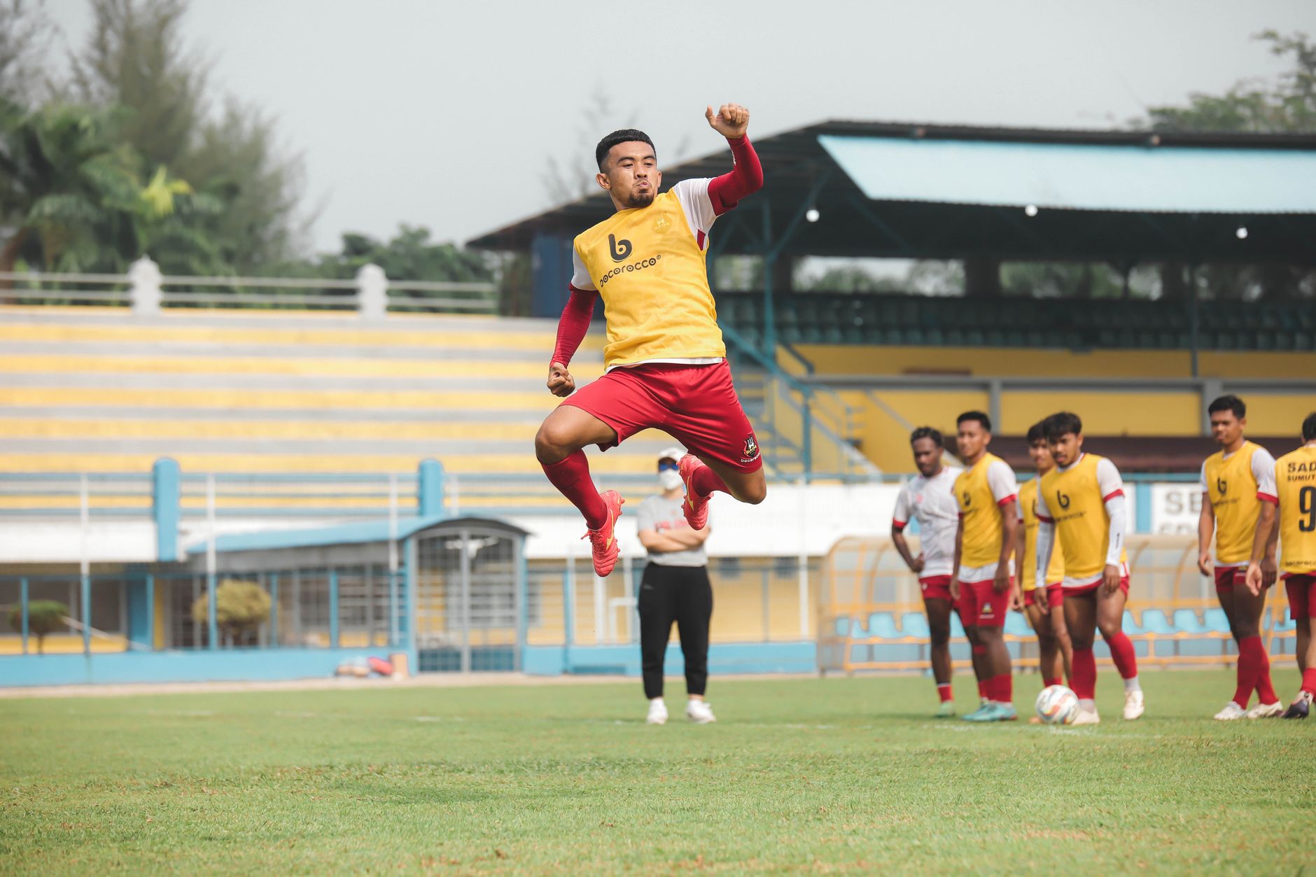 Pemain sepak bola berlatih di lapangan yang cerah di Jakarta, menampilkan atletisme dan kerja tim.