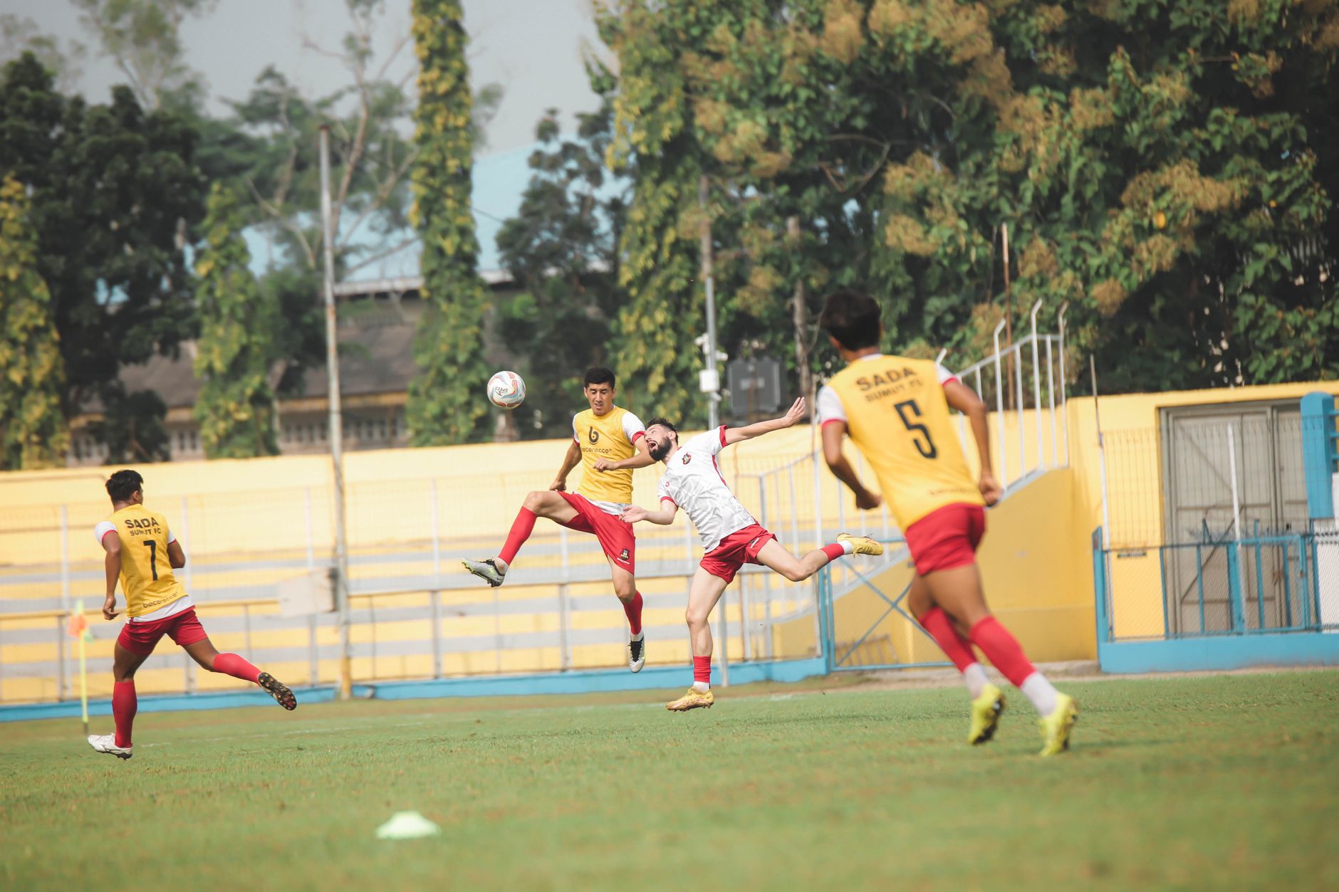Pertandingan sepak bola penuh aksi di stadion Jakarta dengan pemain dalam gerakan yang ditangkap di suasana yang hidup.