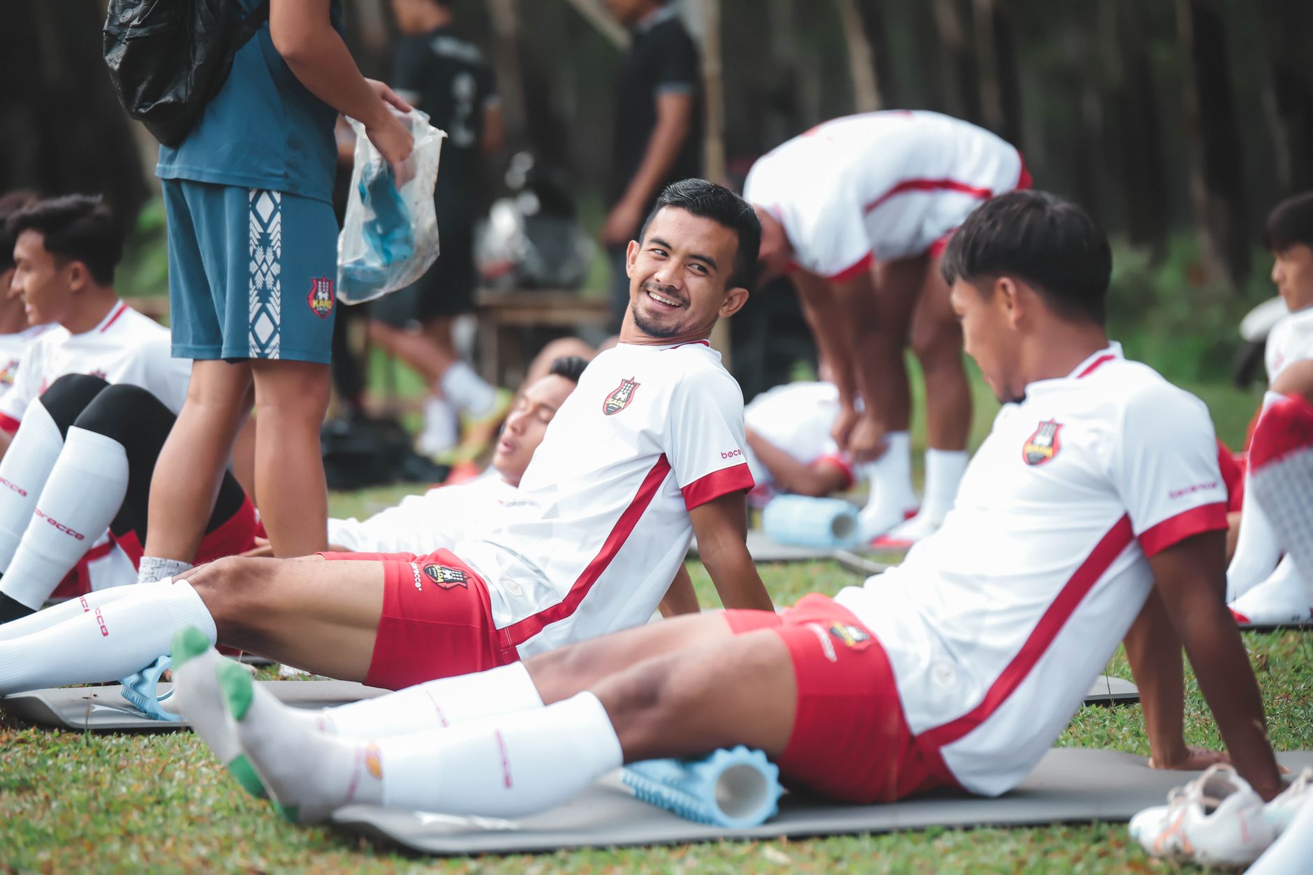 Pemain sepak bola di Jakarta bersantai di atas tikar selama sesi latihan di luar ruangan.