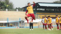 Pemain sepak bola berlatih di lapangan yang cerah di Jakarta, menampilkan atletisme dan kerja tim.