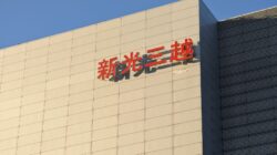 Tampilan eksterior sebuah gedung komersial modern di Taipei yang menampilkan papan nama khas berbahasa Mandarin.