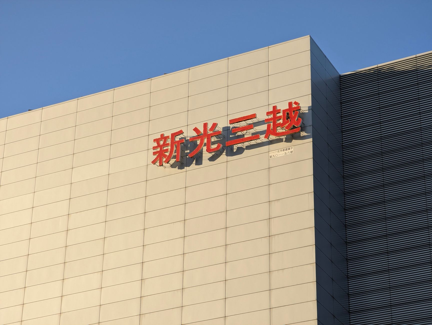 Tampilan eksterior sebuah gedung komersial modern di Taipei yang menampilkan papan nama khas berbahasa Mandarin.