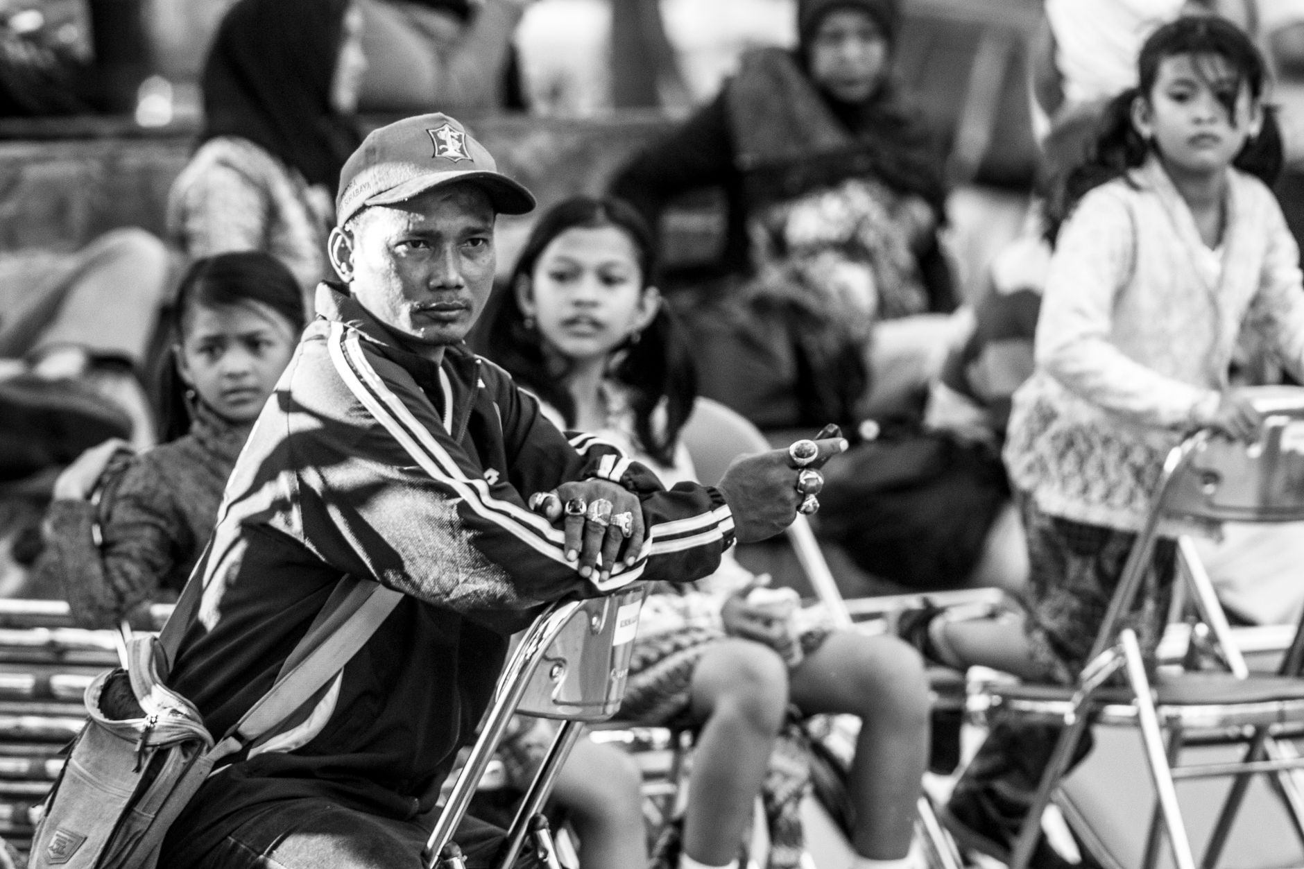 Foto monokrom yang menangkap orang-orang duduk di luar ruangan di Surabaya, Indonesia.