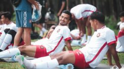 Pemain sepak bola di Jakarta bersantai di atas tikar selama sesi latihan di luar ruangan.