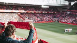 Pendukung sepak bola yang penuh semangat dengan syal di Stadion Anfield, menangkap sensasi pertandingan.