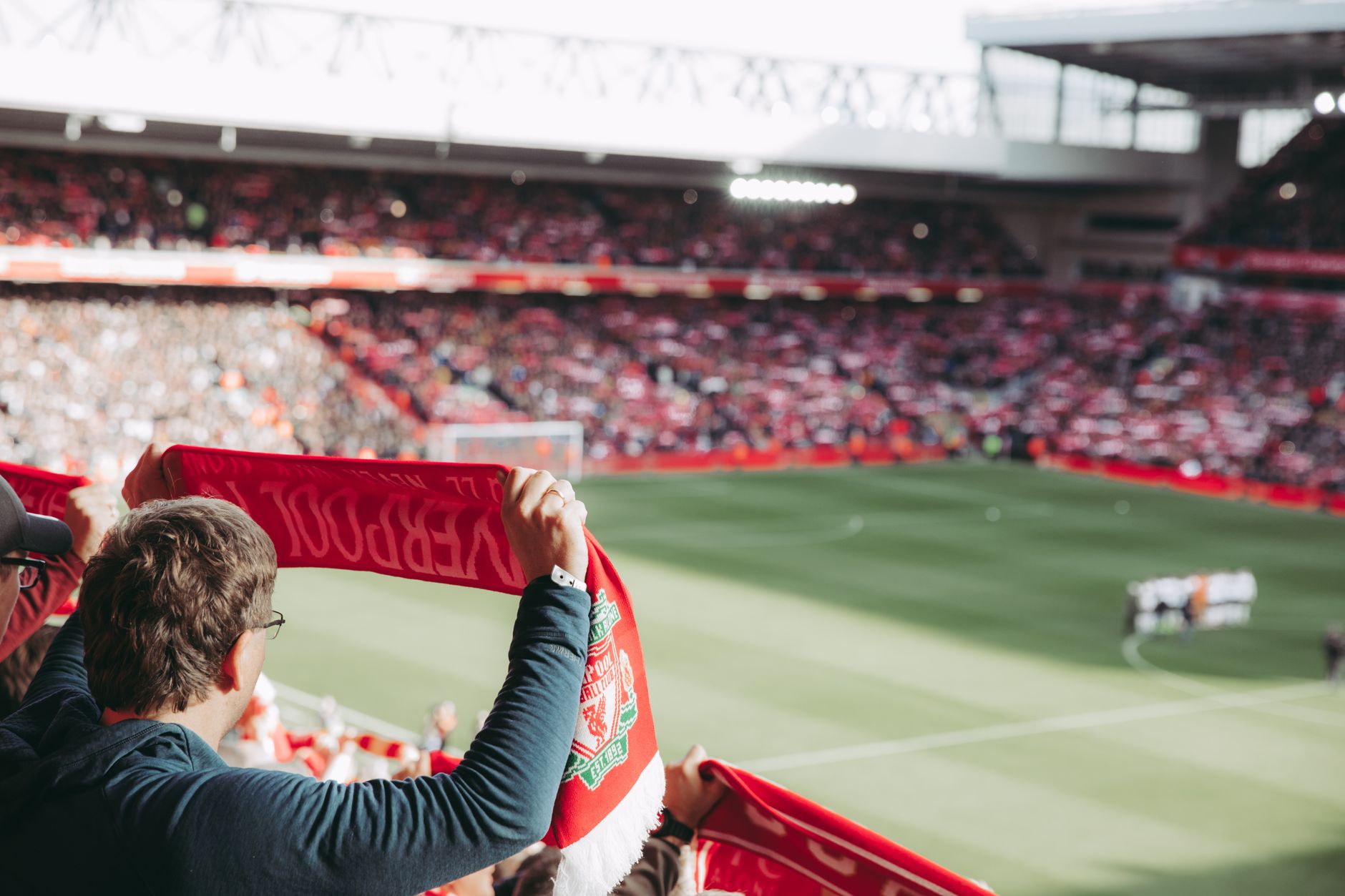 Pendukung sepak bola yang penuh semangat dengan syal di Stadion Anfield, menangkap sensasi pertandingan.