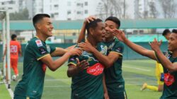 Pemain sepak bola merayakan gol di lapangan dengan semangat dan kerja sama tim.