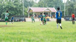 Para pemain sepak bola amatir berkompetisi di lapangan setempat pada hari hujan.