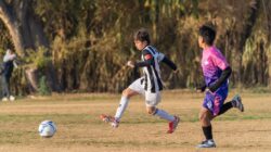 Dua pemain sepak bola muda terlibat dalam pertandingan di hari yang cerah.