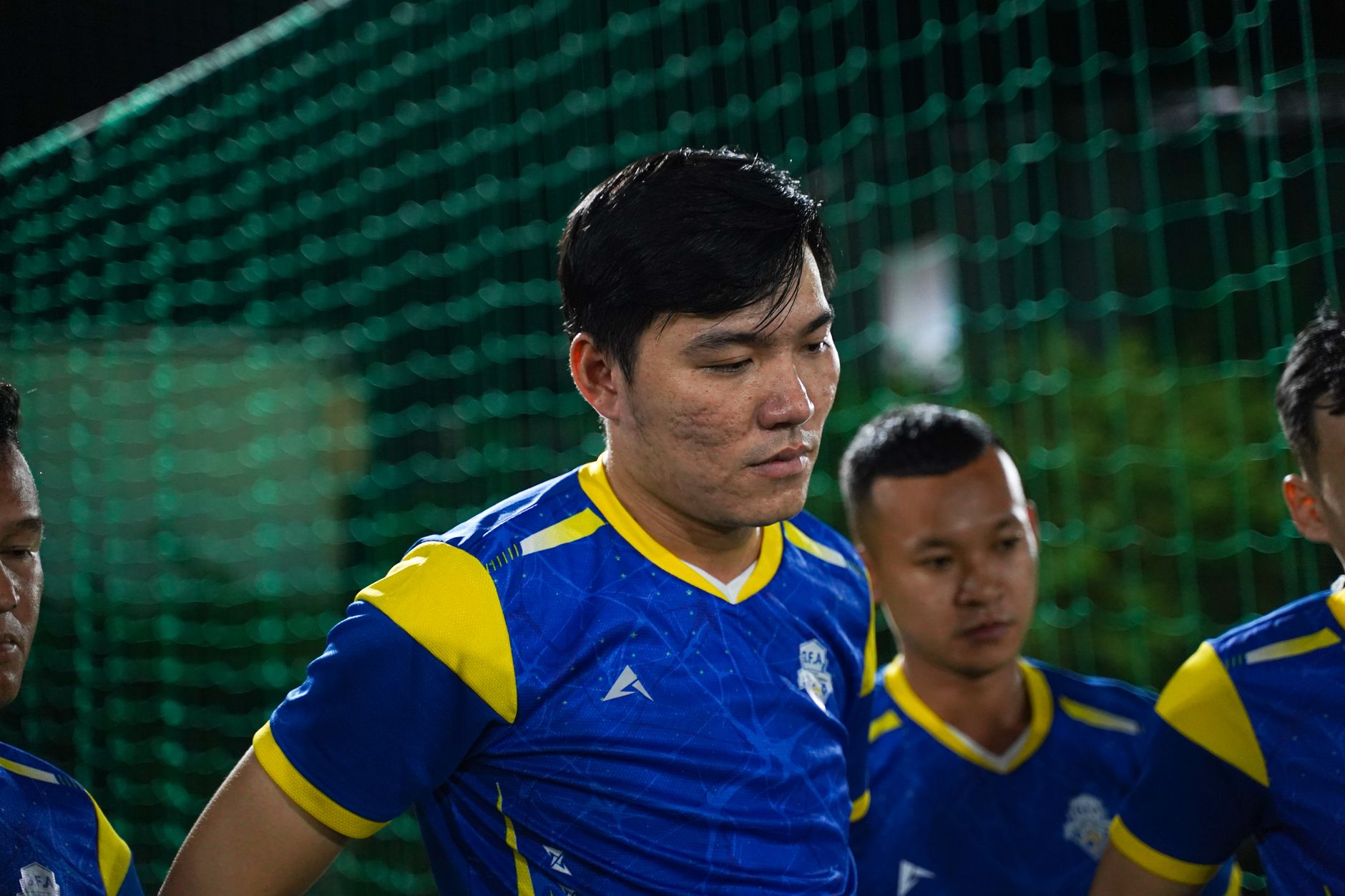 Tim sepak bola Asia berkumpul dalam seragam yang cerah selama pertandingan malam. Fokus pada kerja tim dan sportivitas.
