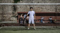 Seorang pemain sepak bola muda berdiri di depan gawang dengan bola di Istanbul, Turki.
