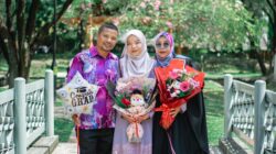 Sebuah keluarga merayakan kelulusan di luar ruangan di Shah Alam, Malaysia, menampilkan busana budaya dan kebahagiaan.