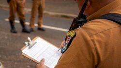 Close-up seorang polisi yang menulis di clipboard di luar ruangan di Londrina, Brasil.