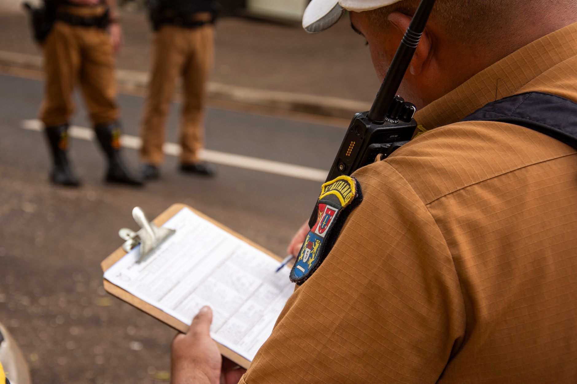 Close-up seorang polisi yang menulis di clipboard di luar ruangan di Londrina, Brasil.
