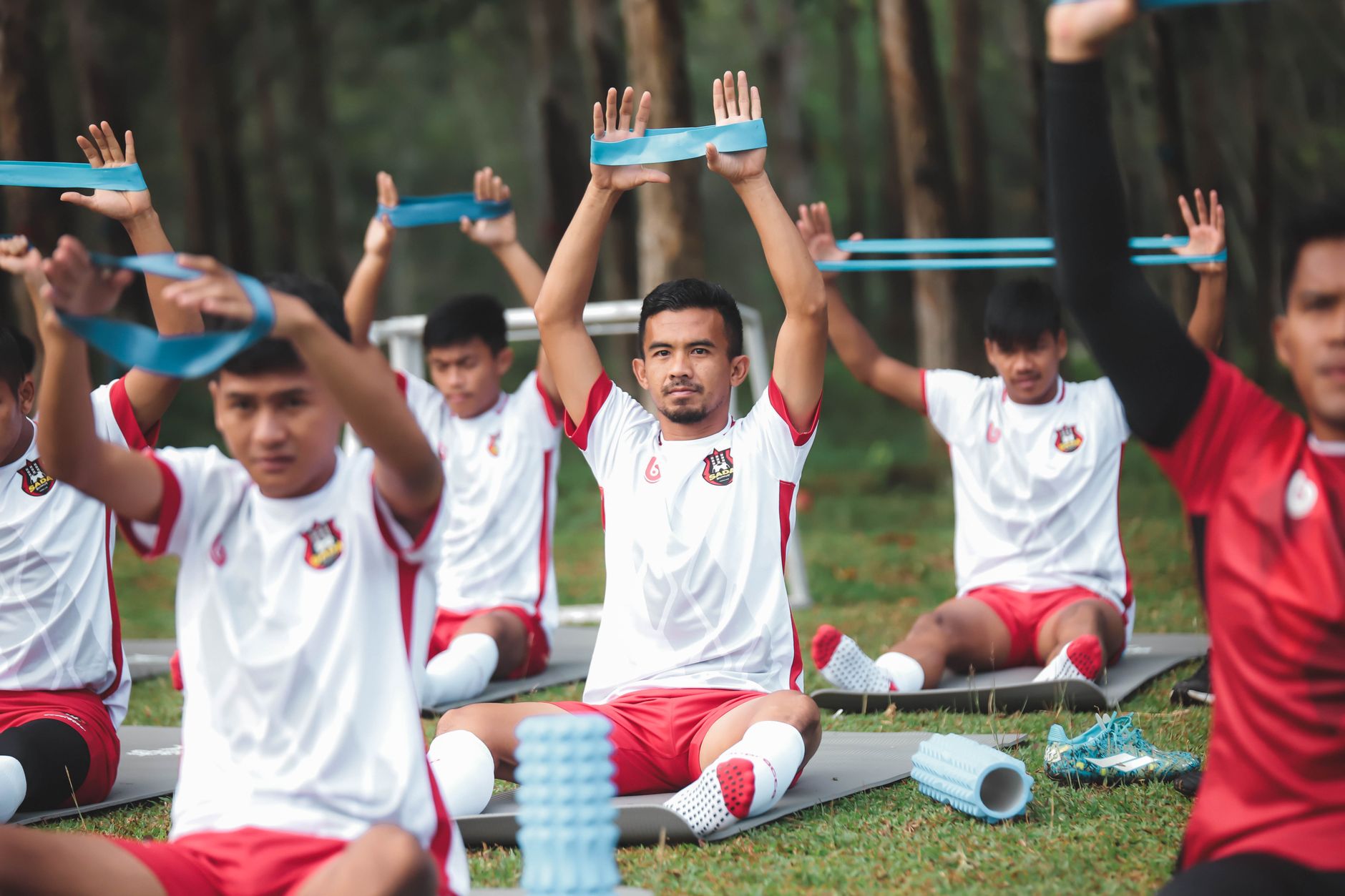 Sekelompok pemain sepak bola muda berlatih dengan band resistensi selama latihan di luar ruangan.