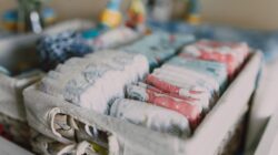Close-up popok bayi berwarna yang tertata rapi dalam keranjang anyaman, ideal untuk organisasi ruang bayi.