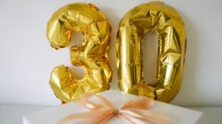 Balon 30 emas dengan kotak hadiah yang dibungkus untuk perayaan atau ulang tahun ke-30.