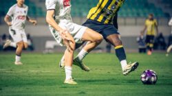 Aksi sepak bola dinamis yang menangkap pemain dalam gerakan selama pertandingan kompetitif.