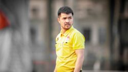 Pelatih sepak bola yang fokus mengenakan kemeja kuning selama sesi latihan luar ruangan di Hanoi, Vietnam.