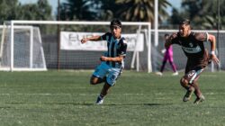 Dua pemain sepak bola muda laki-laki berlari kencang selama pertandingan luar ruangan yang sengit di hari yang cerah.