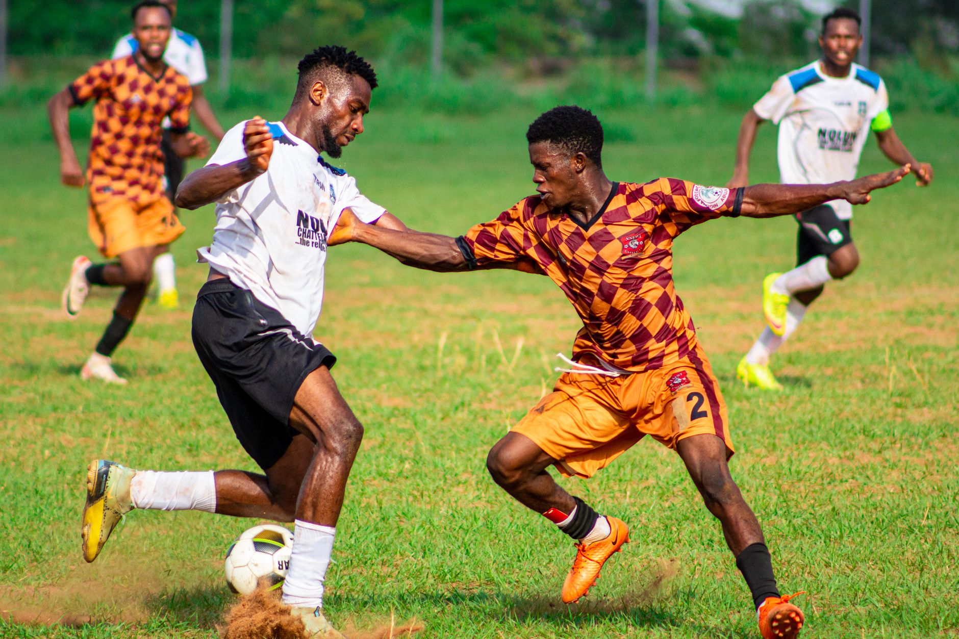 Pemain dalam aksi selama pertandingan sepak bola kompetitif di luar ruangan.