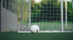 Close-up bola sepak di lapangan luar dengan jaring gawang, sempurna untuk tema olahraga.