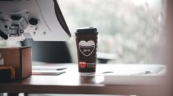 Cangkir kopi bermerek McCafe di meja kantor modern, menciptakan suasana kerja yang santai.