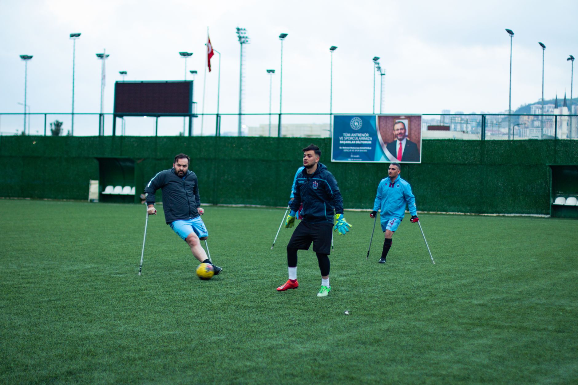 Atlet adaptif bermain sepak bola di lapangan, menunjukkan keterampilan dan tekad.