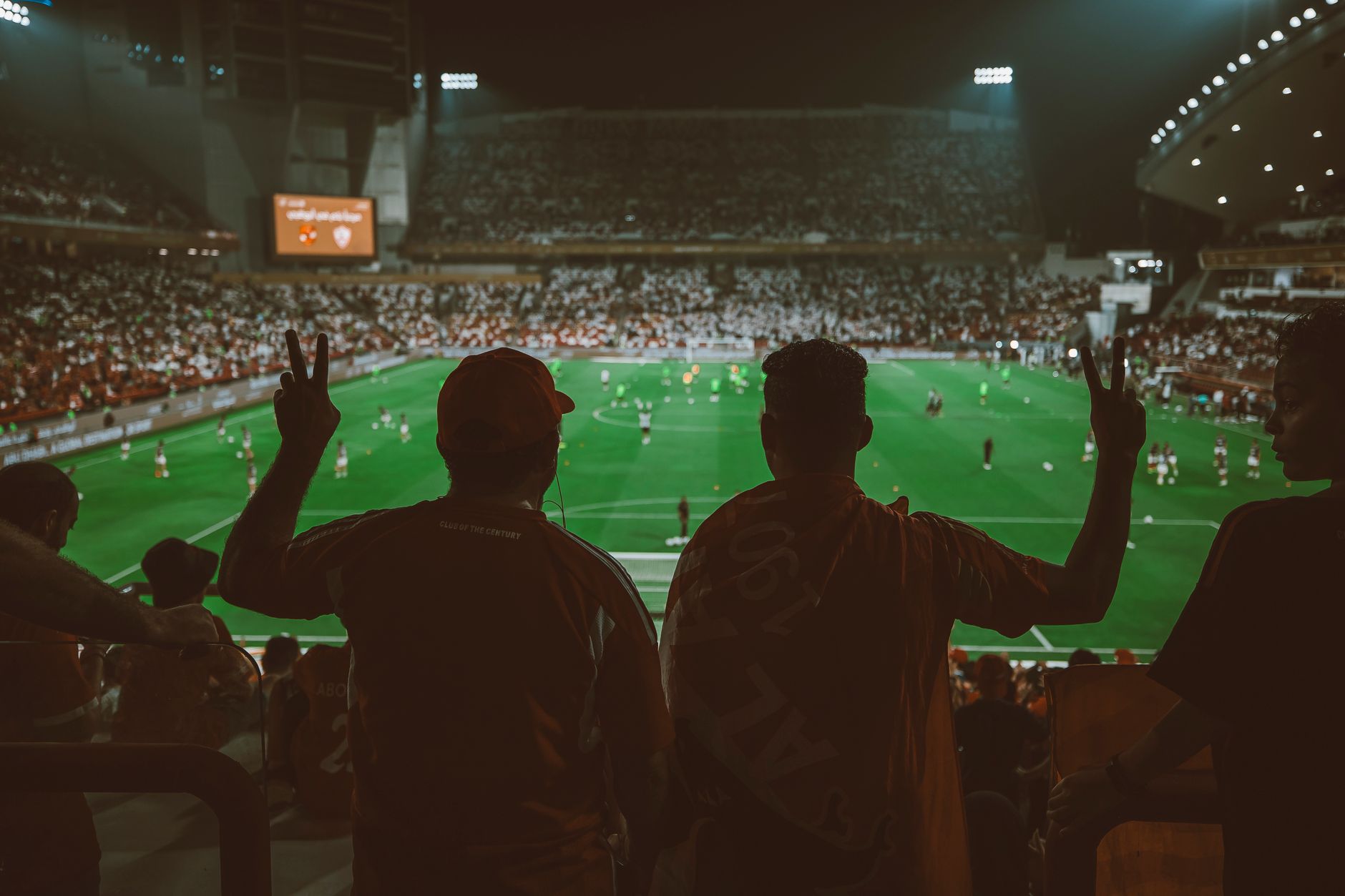 Pertandingan sepak bola yang meriah dengan para penggemar yang bersorak di stadion yang terang.